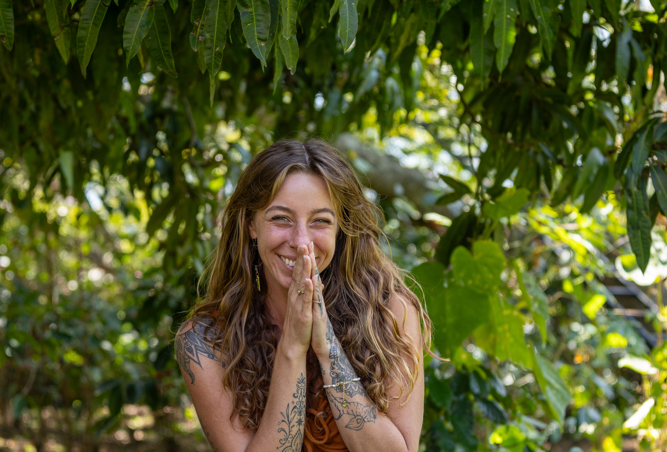 Chrystee seated in a jungle garden with her hands at her heart