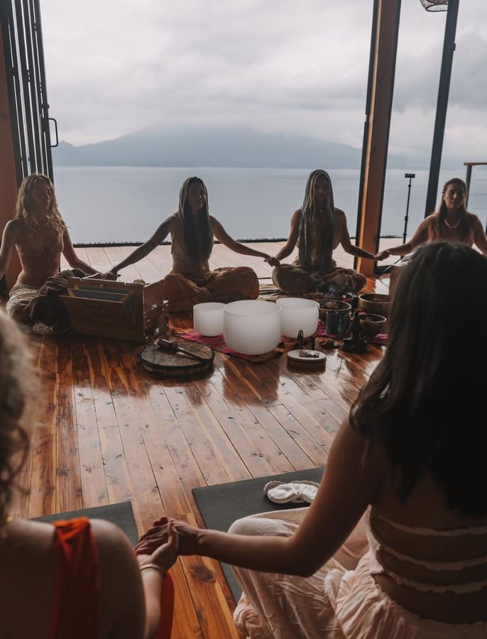 A sound bath circle on a wooden deck above the lake