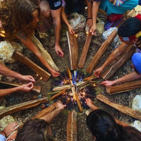 Hands laying logs into a closing fire