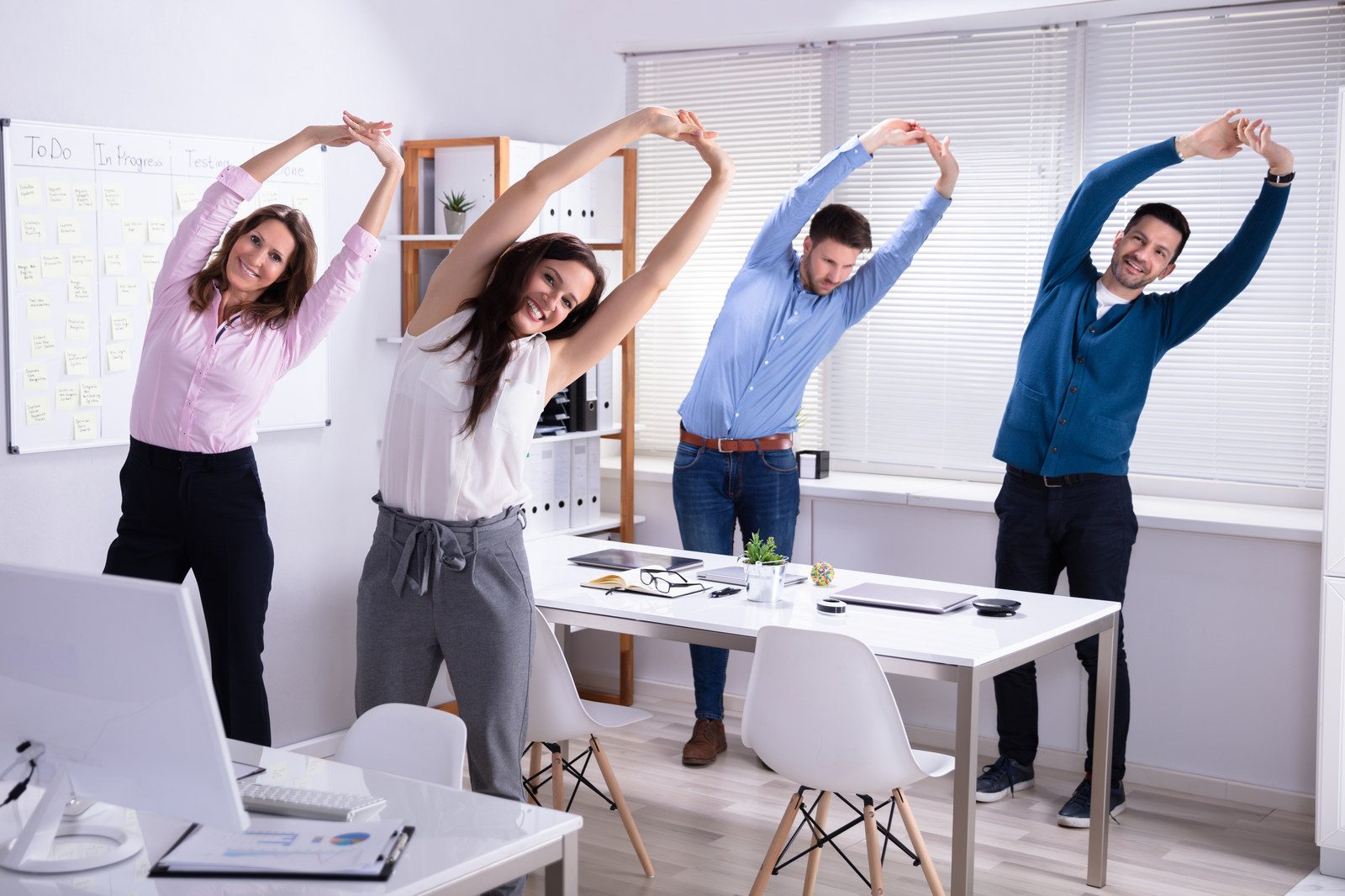 A team stretching together beside a meeting table